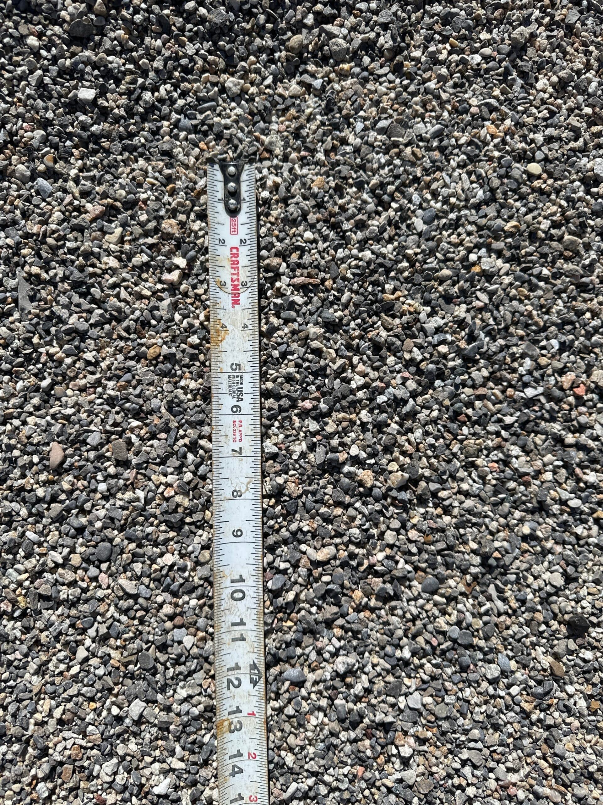 Darby Pit, Gravel & Trucking - We specialize in supplying a wide range of materials including dirt, sand, gravel, and crushed stone. Additionally, we offer top-notch trucking services to support all your excavation needs. Whether you're involved in landscaping projects, home construction, road building, path creation, driveway installation, or laying foundations, we've got you covered. In our latest project showcase: a measuring tape extended to 12 inches rests on a surface beautifully covered in Pea Gravel. This demonstrates the precision and quality of materials we provide for any scale of work.