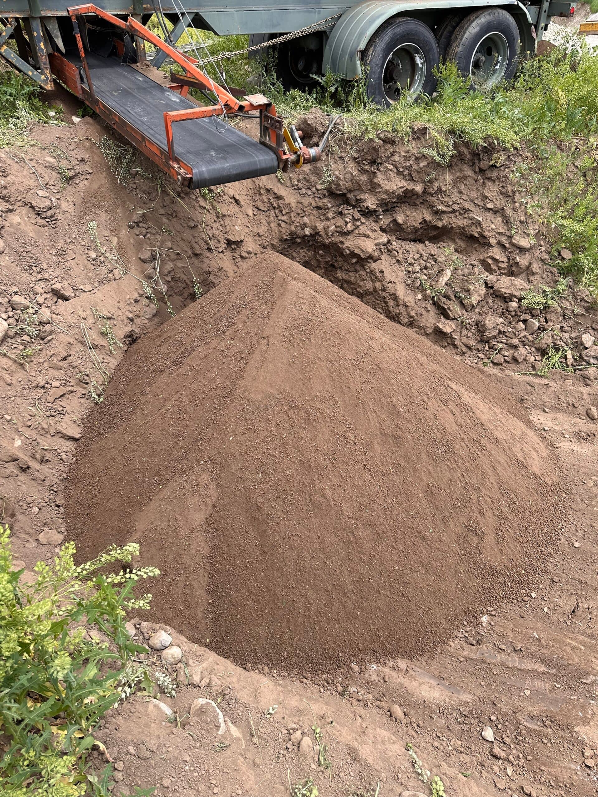 Darby Pit, Gravel & Trucking - We specialize in supplying a comprehensive range of materials such as dirt, sand, gravel, and crushed stone. These materials are essential for a variety of projects including excavation work, landscaping enhancements, home building endeavors, road construction, pathway creation, driveway laying, and foundation establishment. Our services extend to providing efficient trucking solutions to ensure timely delivery of these materials. Imagine a large pile of rich dirt being expertly unloaded from one of our trucks via a state-of-the-art moving conveyor belt system. This efficient process takes place in strategically dug-out areas surrounded by lush greenery—perfect for your specific project needs. Whether you're building the perfect garden path or laying the groundwork for a new home or roadway, we’re here to support you every step of the way with top-quality materials and reliable service.