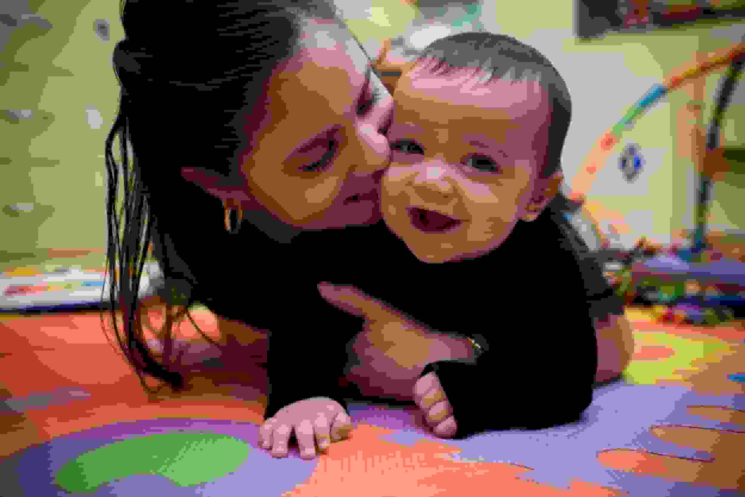 Adorable hispanic young mother and son in home playroom