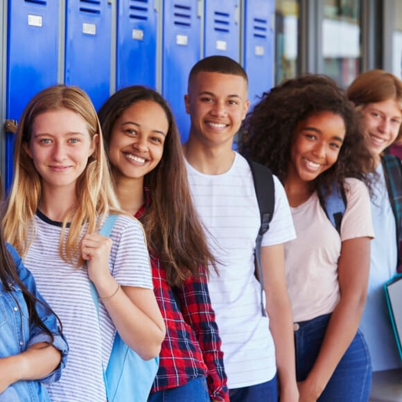 Teenage School Kids Smiling To Camera In School Corridor