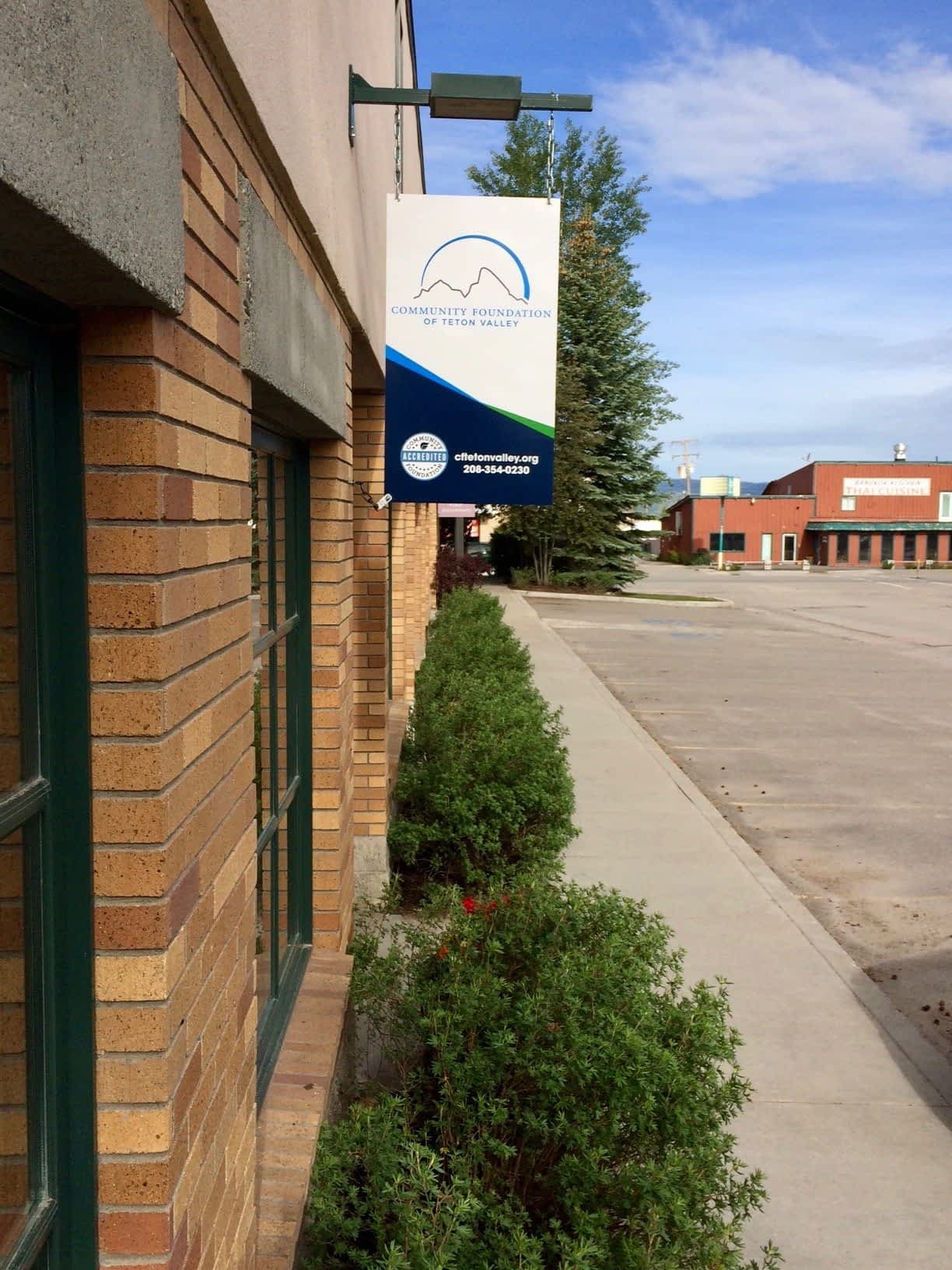 Teton Valley Non-Profits, A sturdy brick building proudly displays a sign for the Community Foundation of Teton Valley, symbolizing its pivotal role in fortifying the local community. Neatly trimmed bushes frame the sidewalk, offering a welcoming approach to the foundation’s headquarters. Here, amidst a backdrop of other structures, this organization stands out as a beacon of generosity and support. The Community Foundation of Teton Valley collaborates intimately with local non-profits and businesses, channeling charitable contributions to drive meaningful change and bolster communal resilience. Through strategic grants and dedicated programs, they empower these entities to thrive and address critical needs within Teton Valley, fostering an environment where collective growth and prosperity flourish. The Tin Cup Challenge & Run is the CFTV annual giving event day.