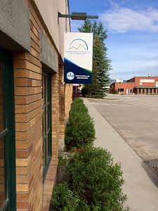 Teton Valley Non-Profits, A sturdy brick building proudly displays a sign for the Community Foundation of Teton Valley, symbolizing its pivotal role in fortifying the local community. Neatly trimmed bushes frame the sidewalk, offering a welcoming approach to the foundation’s headquarters. Here, amidst a backdrop of other structures, this organization stands out as a beacon of generosity and support. The Community Foundation of Teton Valley collaborates intimately with local non-profits and businesses, channeling charitable contributions to drive meaningful change and bolster communal resilience. Through strategic grants and dedicated programs, they empower these entities to thrive and address critical needs within Teton Valley, fostering an environment where collective growth and prosperity flourish. The Tin Cup Challenge & Run is the CFTV annual giving event day.