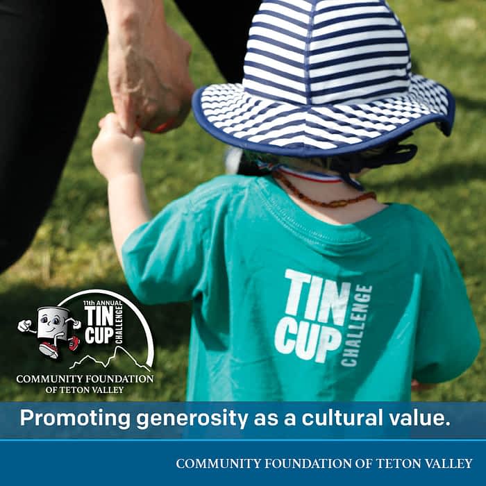 Teton Valley Non-Profits, In the heartwarming image, a child sporting a blue hat and a green shirt emblazoned with the "Tin Cup Challenge" logo on the back is seen holding an adult's hand. This visual encapsulates the essence of community spirit fostered by the Community Foundation of Teton Valley. Through initiatives like the Tin Cup Challenge, this foundation plays a pivotal role in bolstering non-profits and local businesses, channeling charitable giving to fuel their missions. By creating avenues for shared support and growth, they ensure that resources are effectively distributed to benefit the entire community, demonstrating their commitment to collective well-being and sustainability. The Tin Cup Challenge & Run is the CFTV annual giving event day.