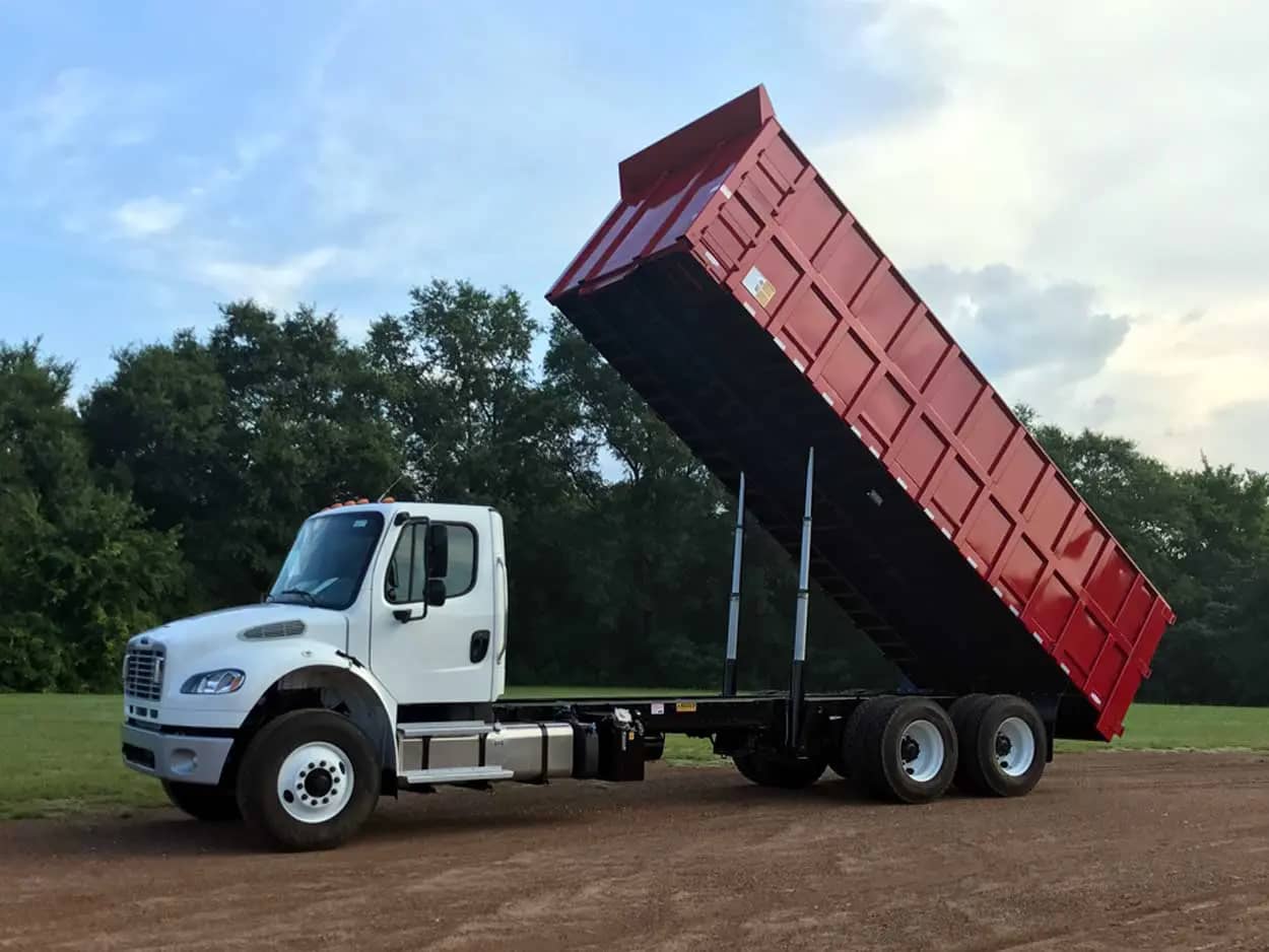 Darby Pit, Gravel & Trucking - We specialize in supplying top-quality dirt, sand, gravel, and crushed stone for all your construction and landscaping needs. Whether you're building roads, paths, driveways, or foundations—or embarking on excavation projects—we have the materials to get the job done right. Our comprehensive trucking services ensure timely delivery to home builders and landscapers alike. Picture a sturdy white dump truck with a red container bed lifted high against a backdrop of verdant trees; it's ready to deliver essential materials straight to your site.